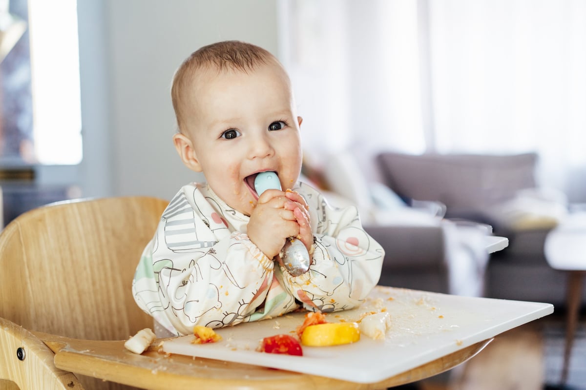 Bebé contento sonriendo mientras se alimenta solo alegre y saludable